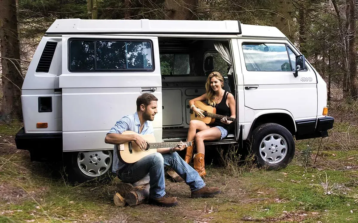 Musicians playing Traveler guitars beside a van